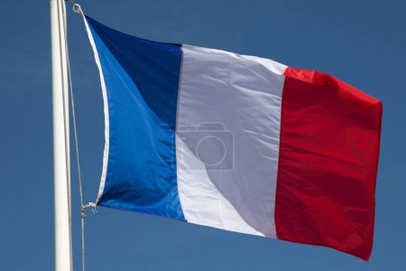 Französische Flagge auf Mast schwebt im Wind am blauen Himmel