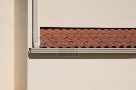 aluminum beige gutter on modern roof of the building and downpipe on facade wall home