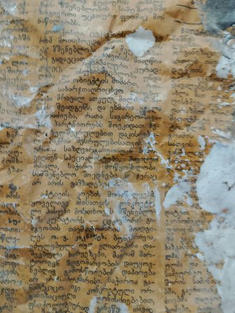 A grungy, aged parchment or paper surface covered in an ornate, indecipherable handwritten script or text, with stains, discoloration, and a mottled tan and blue-grey patina creating an antique, distressed texture backdrop.