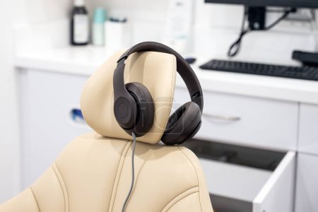 Foto de La sala de tratamiento de la oficina del dentista tiene auriculares bloqueadores de ruido para que el paciente se relaje durante la limpieza de dientes. - Imagen libre de derechos