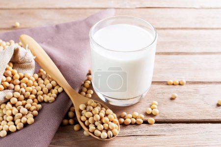 Soy milk in a glass with soybeans on a wooden table Organic breakfast, high protein, healthy, agricultural products, vegetarian