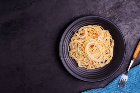Delicious spaghetti pasta with prawns and cheese served in a black bowl on a black background table Italian recipe, tomato sauce, vegetables, and spices top view with copy space Poster 624956448