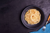Delicious spaghetti pasta with prawns and cheese served in a black bowl on a black background table Italian recipe, tomato sauce, vegetables, and spices top view with copy space Poster #624956448