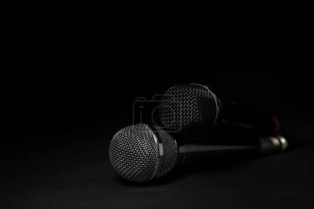Schwarz-silberne Mikrofone im Studio auf schwarzem und dunklem Hintergrund. Professionelle Aufnahmegeräte. Ansicht von oben.