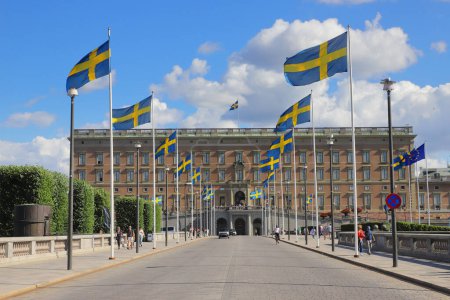 Foto de Estocolmo, Suecia - 14 de julio de 2023: Banderas suecas izadas fuera del palacio real en el puente de Norrbo. - Imagen libre de derechos