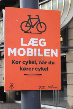 Photo for Copenhagen, Denmark - October 22, 2023: Placard outside the central station with a road safety campaign in Danish that urges "Put down the phone. Ride a bike when you ride a bike". - Royalty Free Image
