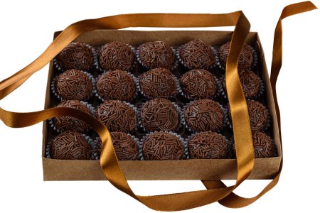Box with several brigadeiros lined up next to a ribbon. Brazilian traditional sweet_white background.