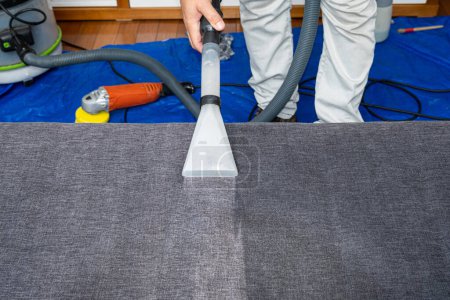 Photo for Man using a special vacuum to clean sofa cushions. - Royalty Free Image