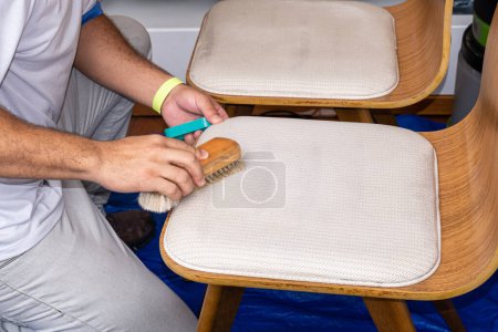 Foto de Limpieza del hombre con un cepillo y preparación de la tapicería de la silla para recibir el líquido. - Imagen libre de derechos