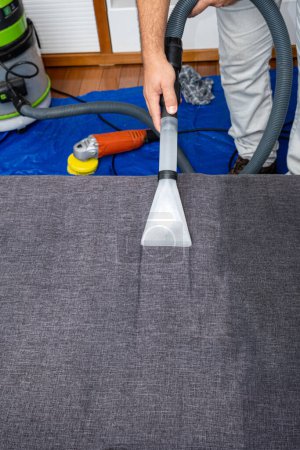 Foto de Hombre usando un vacío especial para limpiar cojines del sofá _ vertical. - Imagen libre de derechos