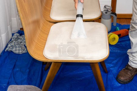 Foto de Hombre usando un vacío especial para limpiar la tapicería de la silla. - Imagen libre de derechos