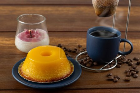 Kleine Quindim, traditionelle brasilianische Süßigkeit, neben einer Tasse Kaffee und einer Kerze _ 4.