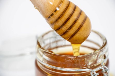 closeup of jar of honey with honey dipper