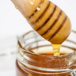 closeup of jar of honey with honey dipper