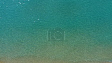 Foto de Movimiento lento de agua transparente lavando la orilla arenosa de la isla tropical. Vista aérea desde arriba. - Imagen libre de derechos