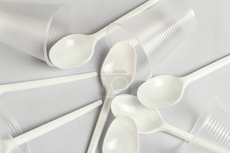 Foto de Cucharas y tazas de plástico desechables en blanco. Primer plano de los utensilios. - Imagen libre de derechos