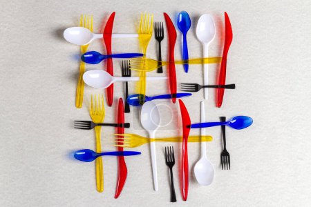 Foto de Vista superior coloridos utensilios de plástico sobre fondo blanco. Tenedores con cucharas y cuchillos. - Imagen libre de derechos