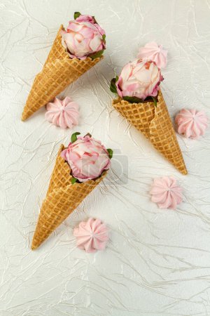 Photo for Ice cream cones with flowers and meringue candy sweets. Vertical shot white background. - Royalty Free Image