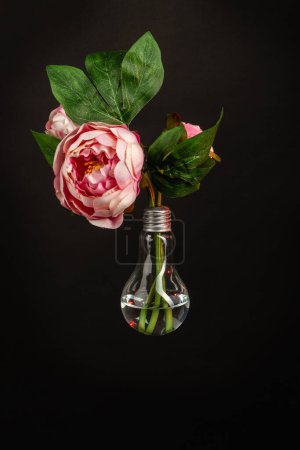Photo for Vertical shot of flower in a light bulb. Isolated on black background. - Royalty Free Image
