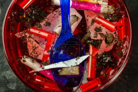 Foto de Vista superior de la basura plastis y cigarrillos en un recipiente con agua. Residuos de plástico y suciedad. - Imagen libre de derechos
