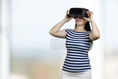 Téléchargez les photos : Young woman is having virtual reality experience. Bright blurred background. - en image libre de droit