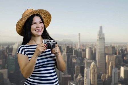 Foto de Happy young tourist korean woman with vintage photo camera. City scape background. - Imagen libre de derechos