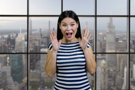 Foto de Portrait of a screaming yelling asian woman indoors. Checkered windows background with cityscape view. - Imagen libre de derechos