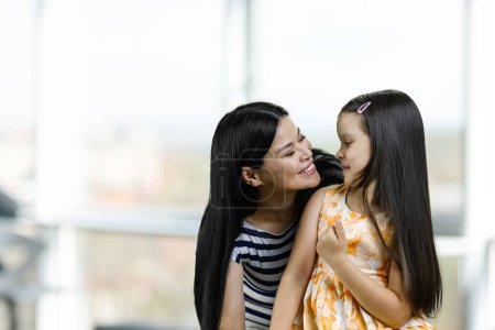 Téléchargez les photos : Portrait of a happy asian mother with her little daughter. Blurred bright background. - en image libre de droit