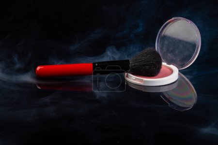 Téléchargez les photos : Round cosmetic powder with mirror and brush. Vapor on black background. - en image libre de droit
