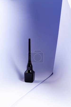 Foto de Vertical shot of black nail polish bottle. White textile background. - Imagen libre de derechos