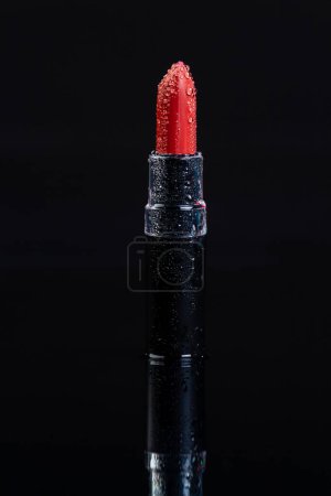 Téléchargez les photos : Gros plan du rouge à lèvres rouge avec des gouttes d'eau. Plan vertical fond noir. - en image libre de droit
