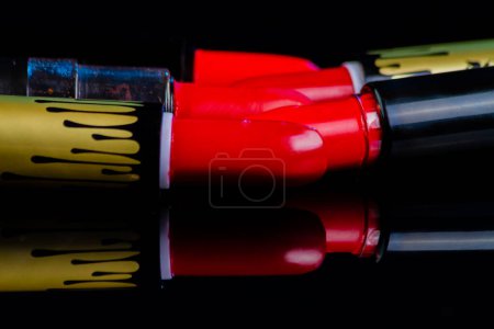 Photo for Close up of red lipsticks on reflective surface. Set of sticks for makeup. - Royalty Free Image
