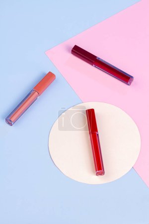 Téléchargez les photos : Three red lip gloss sticks on light blue background. Vertical shot top view. - en image libre de droit