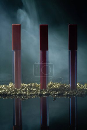 Téléchargez les photos : Vertical shot of standing luxury lip gloss sticks. Steam on the background. - en image libre de droit