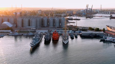 Téléchargez les photos : Navires militaires et touristiques dans le port maritime. Infrastructures maritimes dans le contexte du coucher du soleil. - en image libre de droit