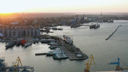 Téléchargez les photos : Vue par drone du port maritime urbain avec des cargos et des terminaux céréaliers. Lumière du coucher du soleil du soir. - en image libre de droit