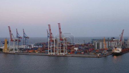 Téléchargez les photos : Port maritime d'Odessa avec conteneurs et grues à tour. Terminaux céréaliers et le navire. Ciel crépusculaire du soir. - en image libre de droit