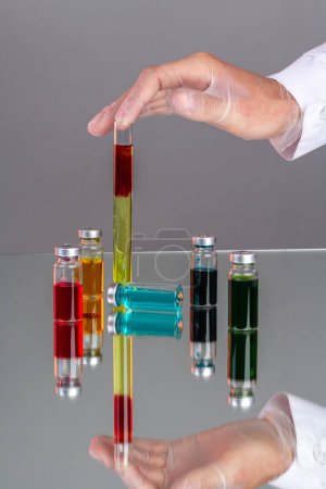 Photo for Hand with glove holding test tube with blood. Drug vials with colored solution. Colorful vaccine bottles. - Royalty Free Image