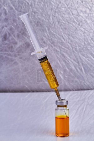 Foto de Jeringa con purpurina dorada se pega en un frasco de vacuna. Disparo vertical de cerca. - Imagen libre de derechos