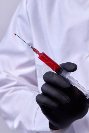 Photo for Close up doctors hand with black glove holding a syringe. - Royalty Free Image