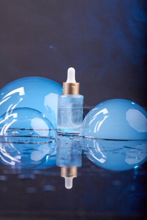 Foto de Frasco de perfume Eau con grandes mitades de burbujas azules. Fondo oscuro plano vertical. - Imagen libre de derechos