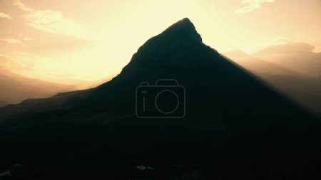 Foto de El sol brilla sobre el pico de la montaña. Cielo azul en el fondo. Escena naturaleza verano. - Imagen libre de derechos