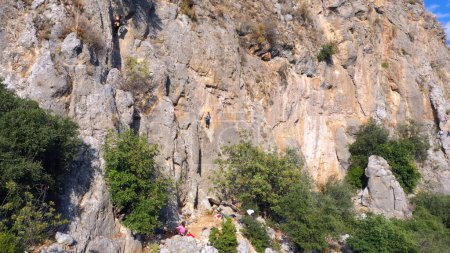 Foto de Un enorme acantilado rocoso de la montaña. Mujer subiendo a la roca. Concepto de turismo y aventura. - Imagen libre de derechos