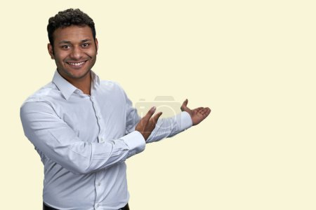 Téléchargez les photos : Portrait d'un homme indien souriant montrant l'espace de copie derrière lui. Isolé sur fond blanc. - en image libre de droit