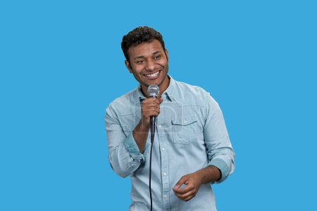Téléchargez les photos : Portrait d'un heureux homme indien joyeux avec microphone. Isolé sur bleu. - en image libre de droit