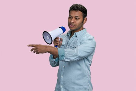 Photo for Young southasian man speaking in megaphone and pointing at something. Isolated on pink background. - Royalty Free Image