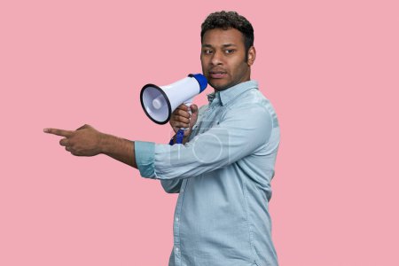 Foto de Joven empresario indio hablando en megáfono y señalando algo. Aislado sobre fondo rosa. - Imagen libre de derechos