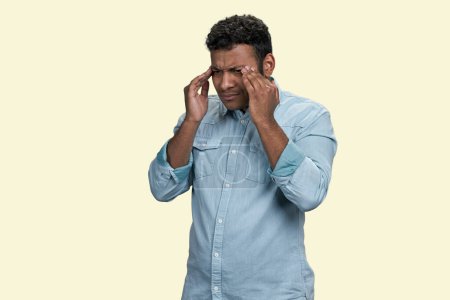 Photo for Young brown indian man touching his head because of headache or migraine pain. Isolated on beige background. - Royalty Free Image