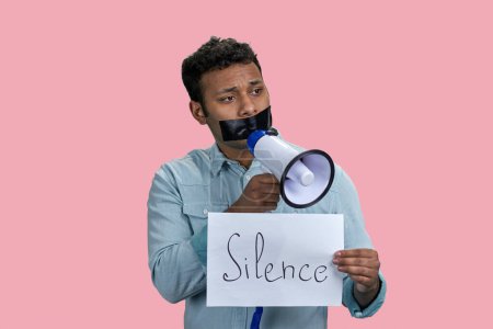 Photo for Indian man taped mouth speaks in megaphone. Censorship and free speech concept. Isolated on pink. - Royalty Free Image