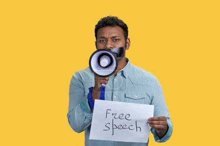 Photo for Portrait of indian man holding sheet of paper and megaphone. Isolated on vivid yellow background. - Royalty Free Image